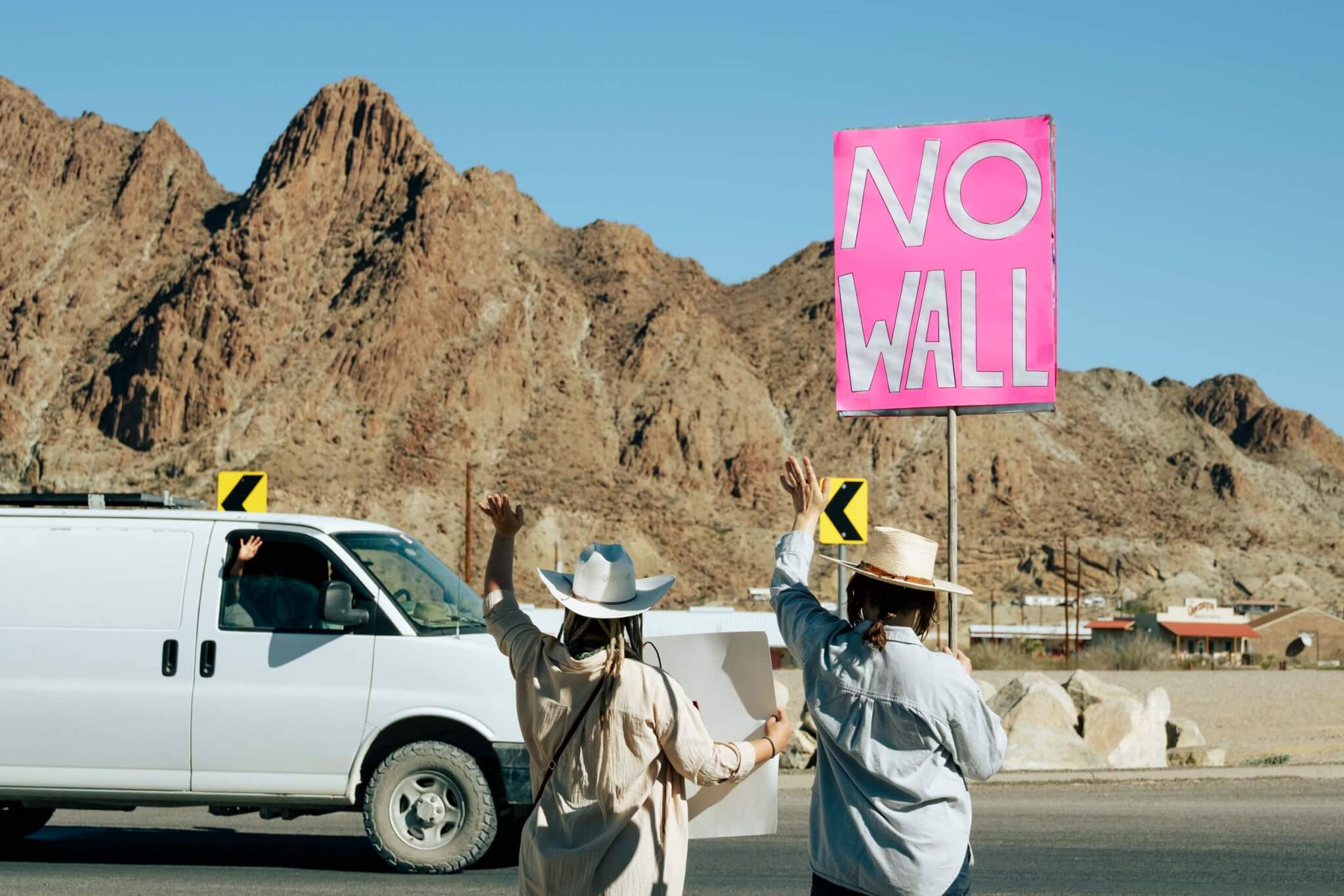 Protesters carry signs against the border wall on February 28 at the intersection of Highway 118 and FM 170 in Terlingua. There were over 100 people in attendance that day, and there were frequent protests at that spot. (Sarah Vasquez)